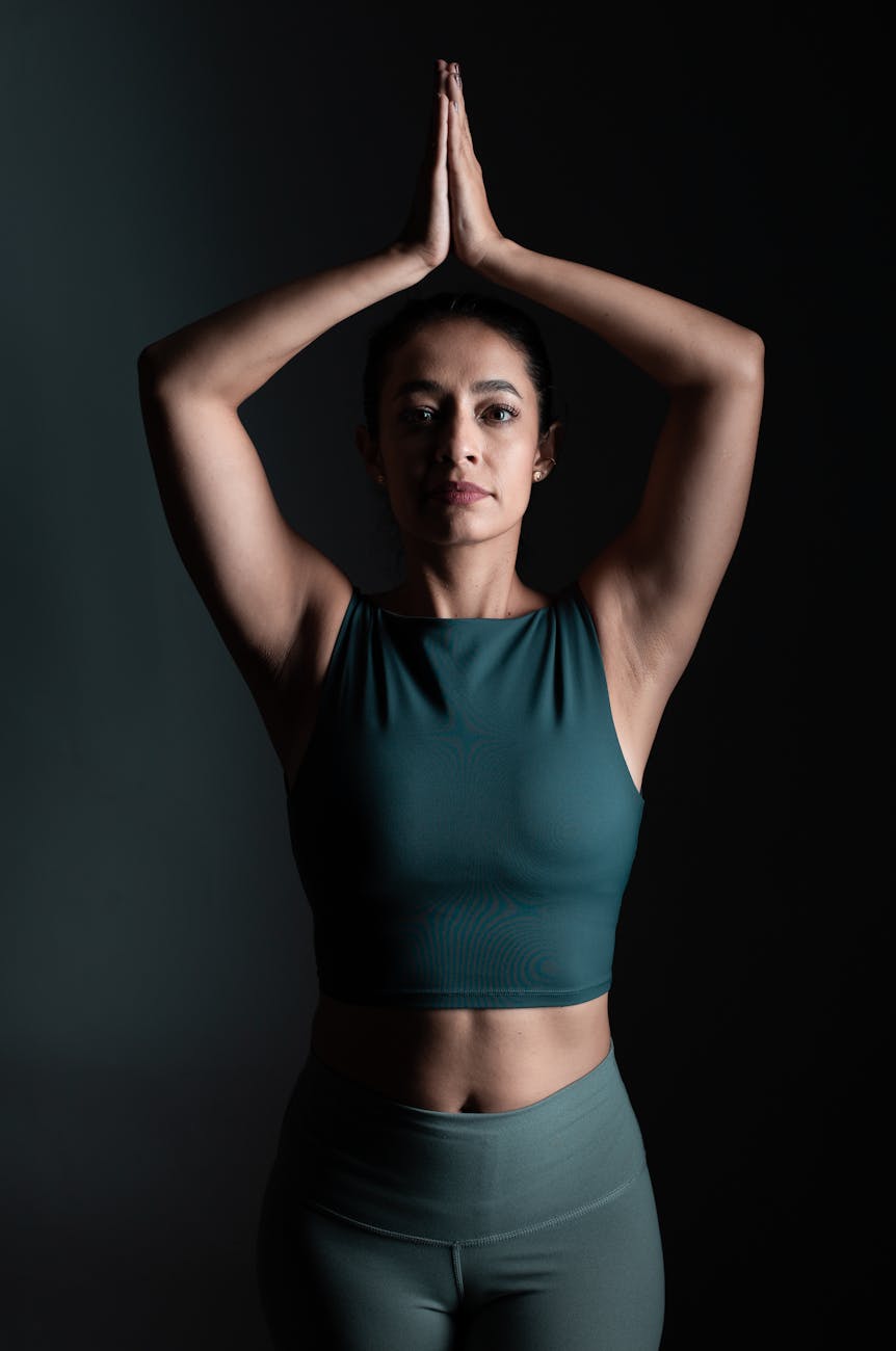 Woman in a calm yoga pose in a dark room with lime green light.